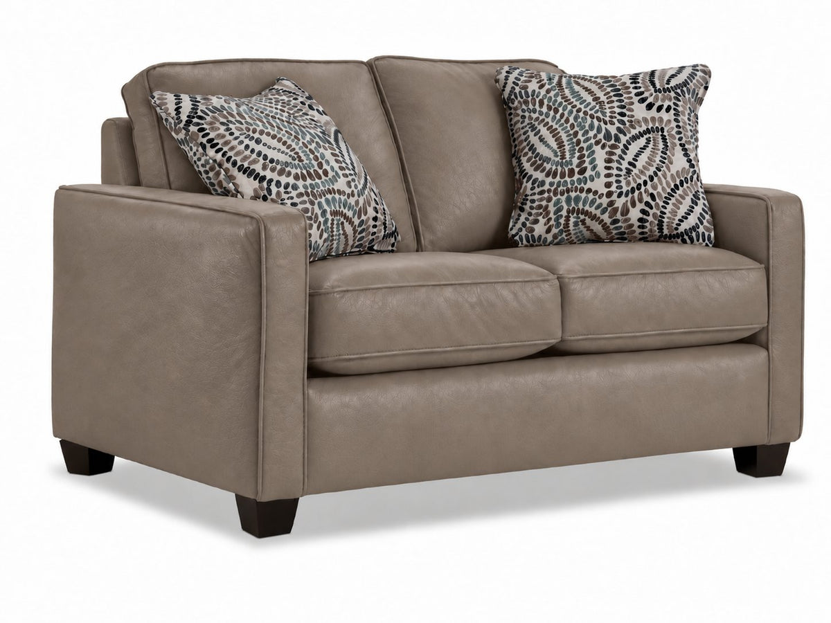 City Leather Loveseat - Stone in a three-quarter view with two seat cushions, patterned accent pillows and dark wood legs