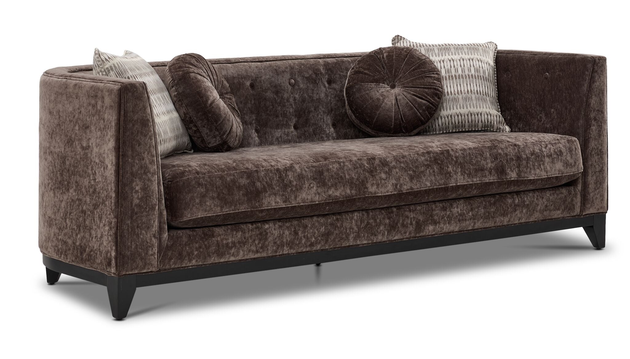 Tresor dark brown sofa with curved back, button-tufted detail, accent pillows and angled front view