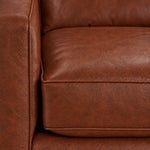 Close-up of the City Leather Chair - Brown showing the leather grain, piped seat cushion and matching upholstered arm
