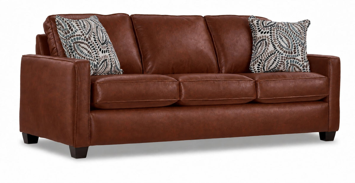 City Leather Sofa - Brown in a three-quarter view with three seat cushions, slim track arms, dark wood legs and two patterned accent pillows