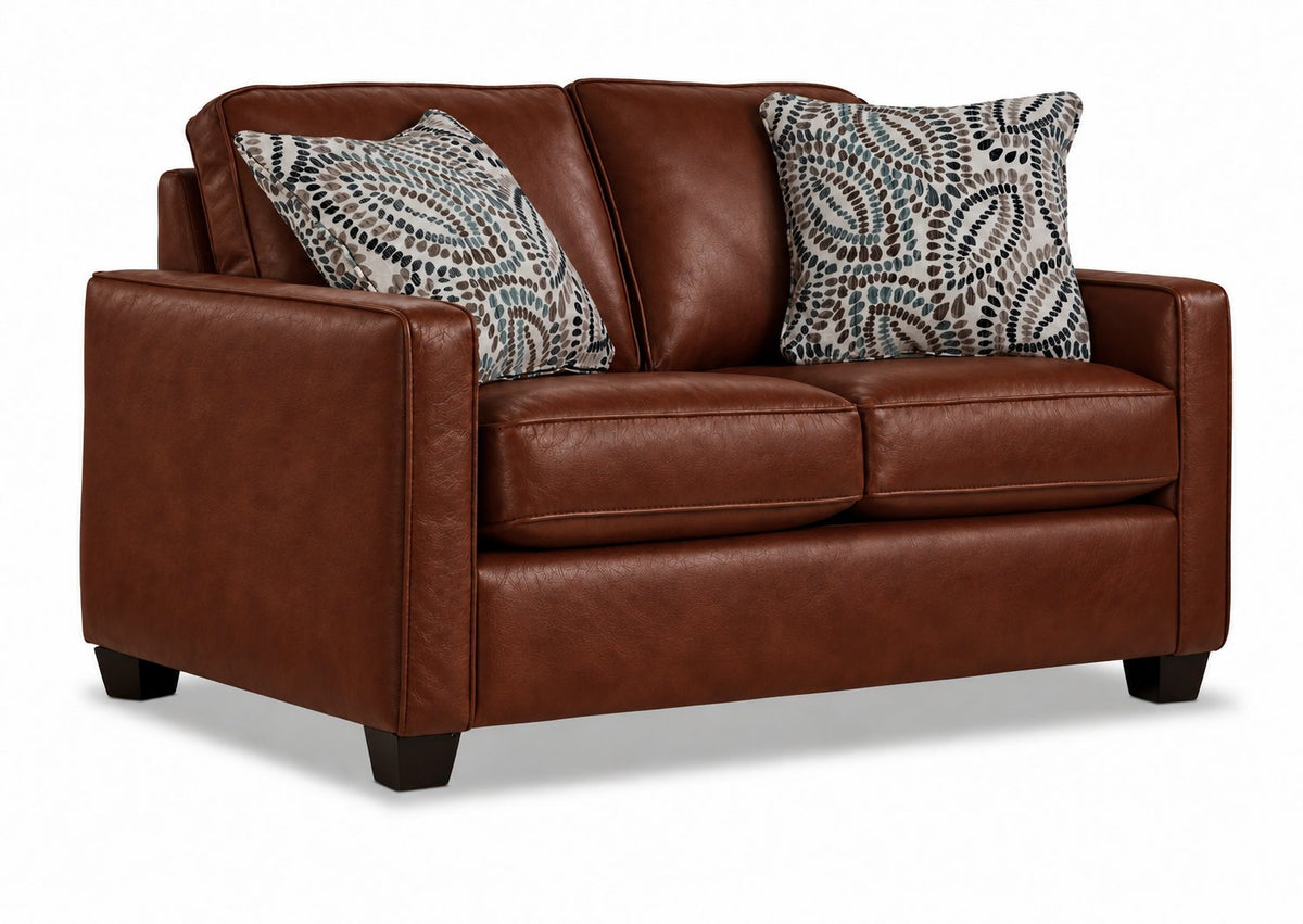 City Leather Loveseat - Brown in a three-quarter view with two cushioned seats, slim track arms, dark wood legs and two patterned accent pillows