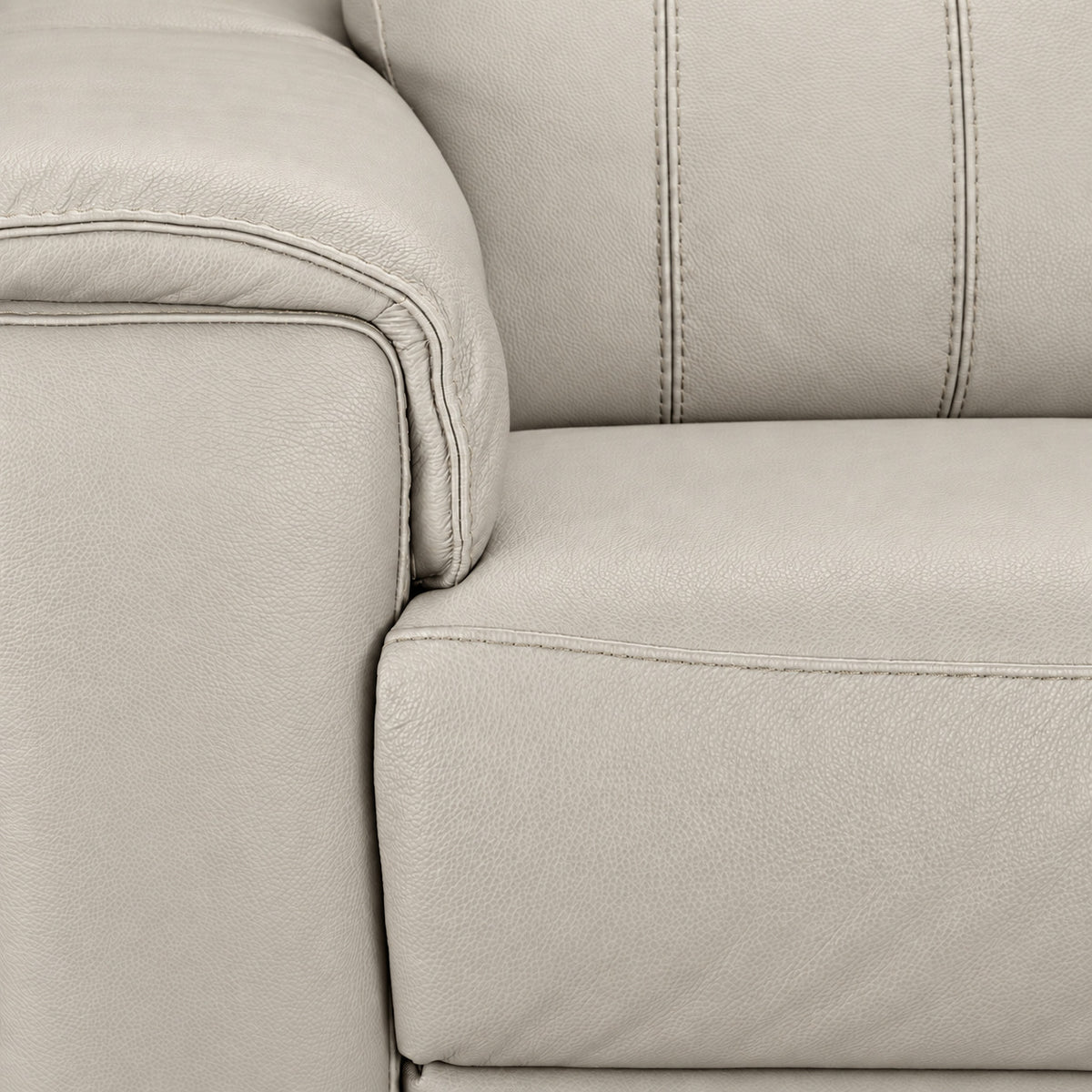Close-up of cream leather upholstery showing grain, stitching, padded arm and seat cushion