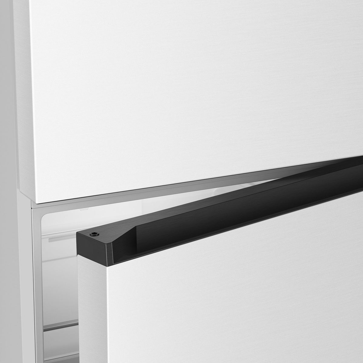Close-up of the black recessed handle between the white freezer and refrigerator doors