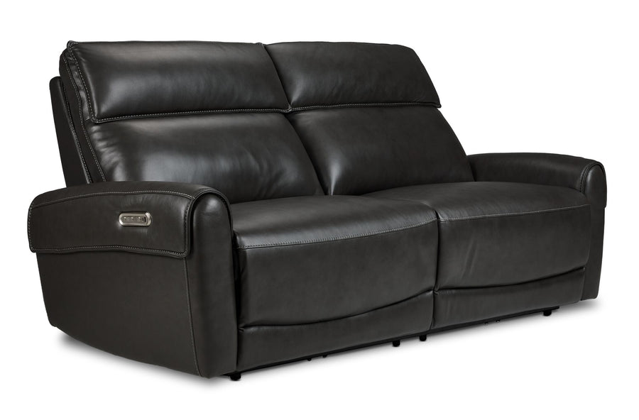 Theo Leather Dual Power Reclining Sofa - Charcoal shown at an angle with plush back cushions, padded armrests and contrast stitching