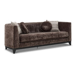 Tresor dark brown sofa with curved back, button-tufted detail, accent pillows and angled front view